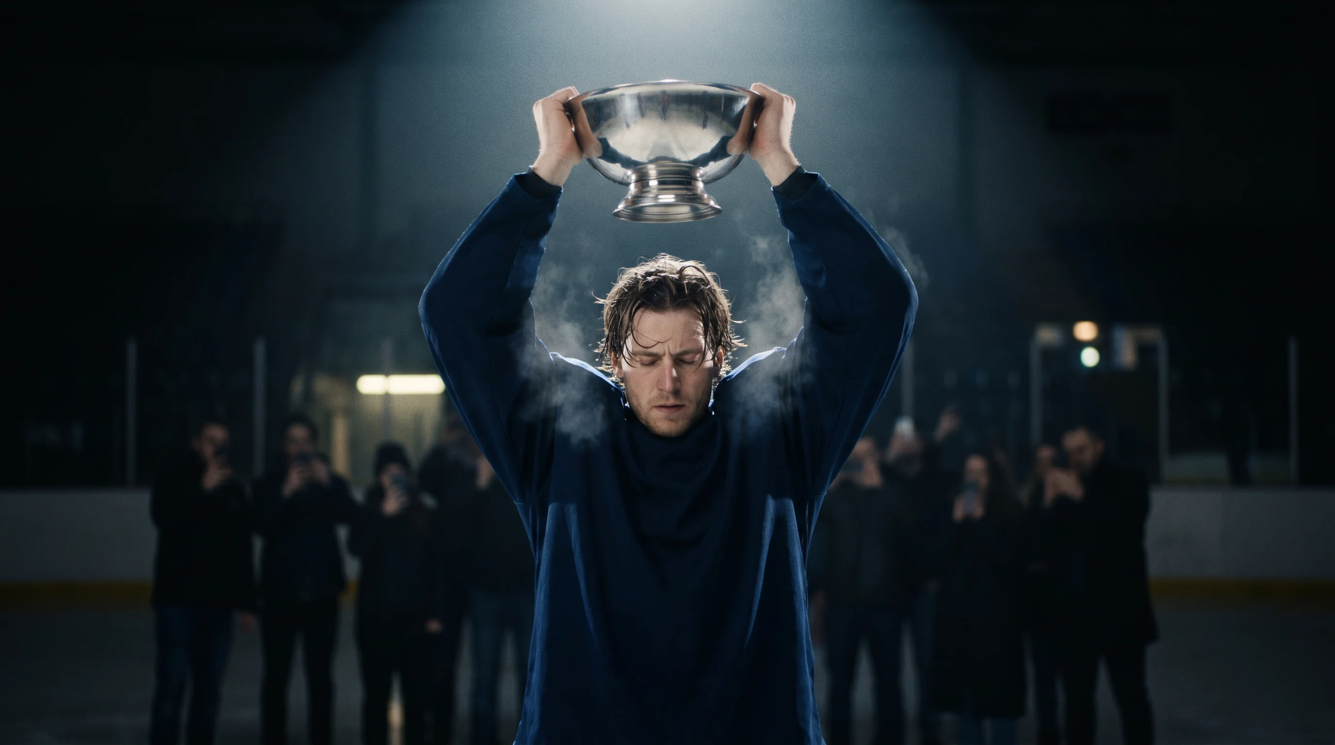 NHL forward holding a regular-season trophy aloft under arena lights