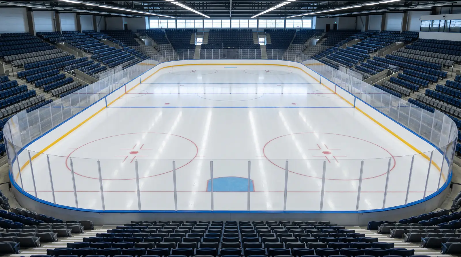 Empty professional ice hockey rink with goal crease, blue lines and centre faceoff dot visible from elevated seating