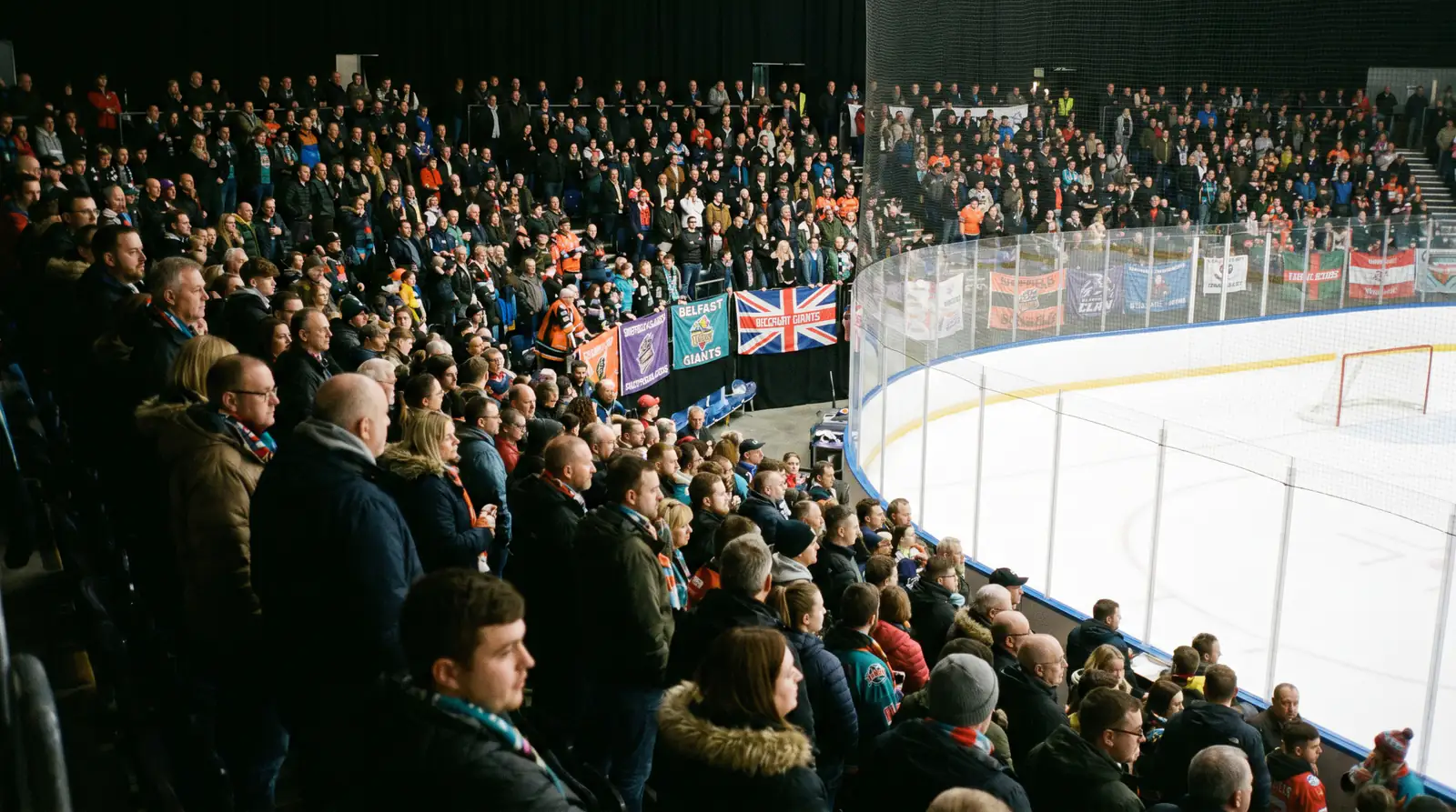 Mixed-fan crowd inside a British arena watching ice hockey from the stands