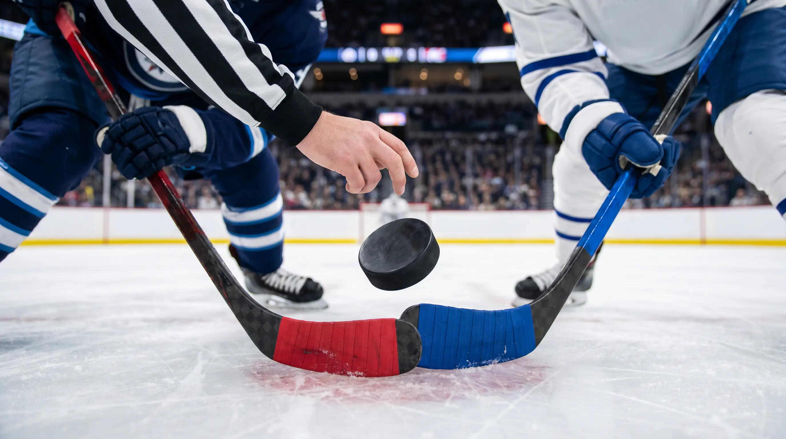 Referee dropping the puck at centre ice to start a new NHL period