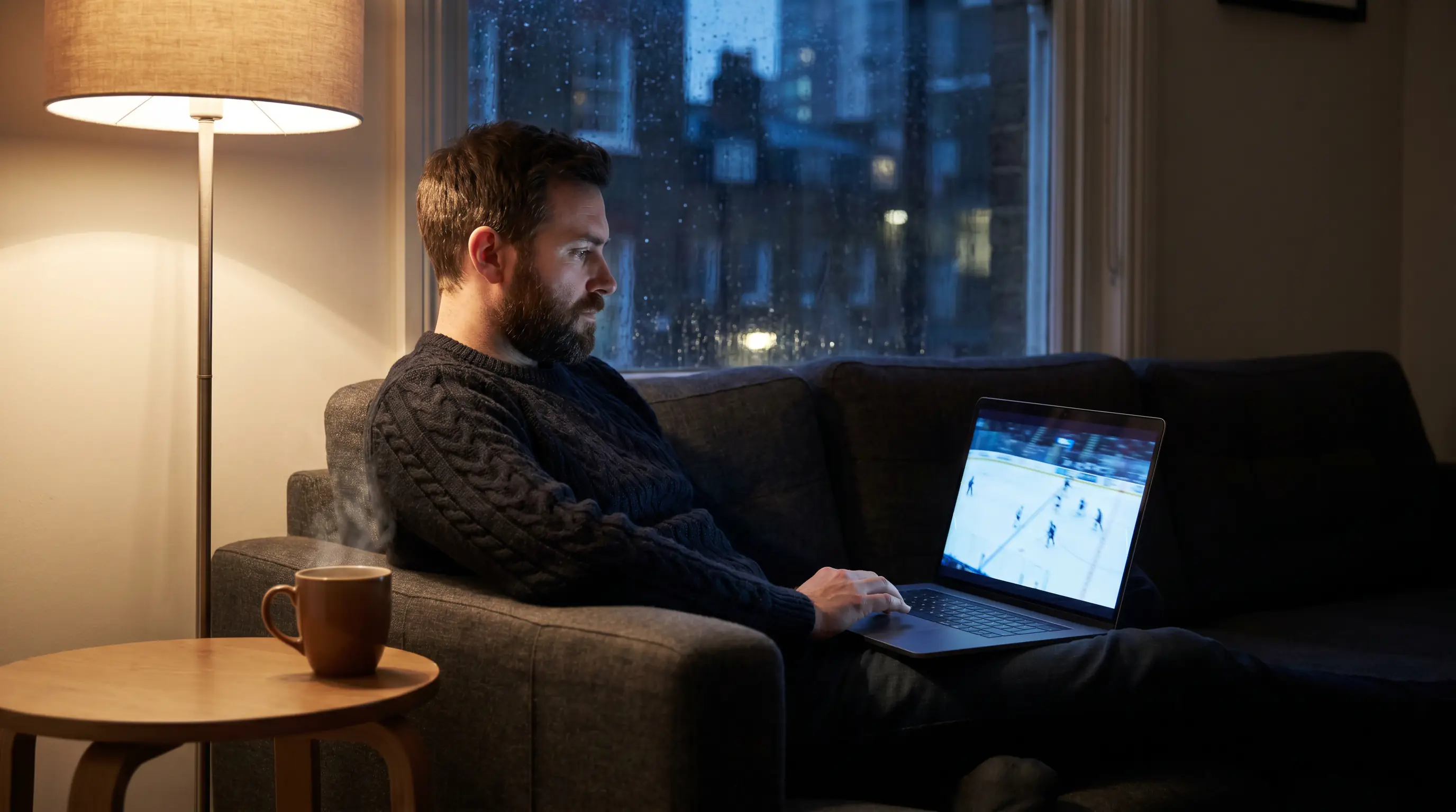 British hockey fan watching an NHL game on a laptop in a dim London living room